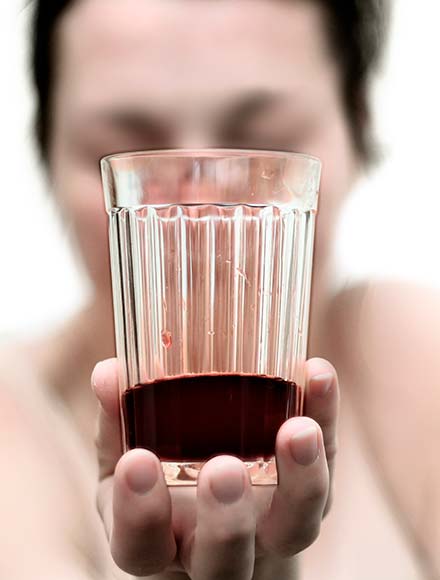 женщина держит перед собой стакан с вином
